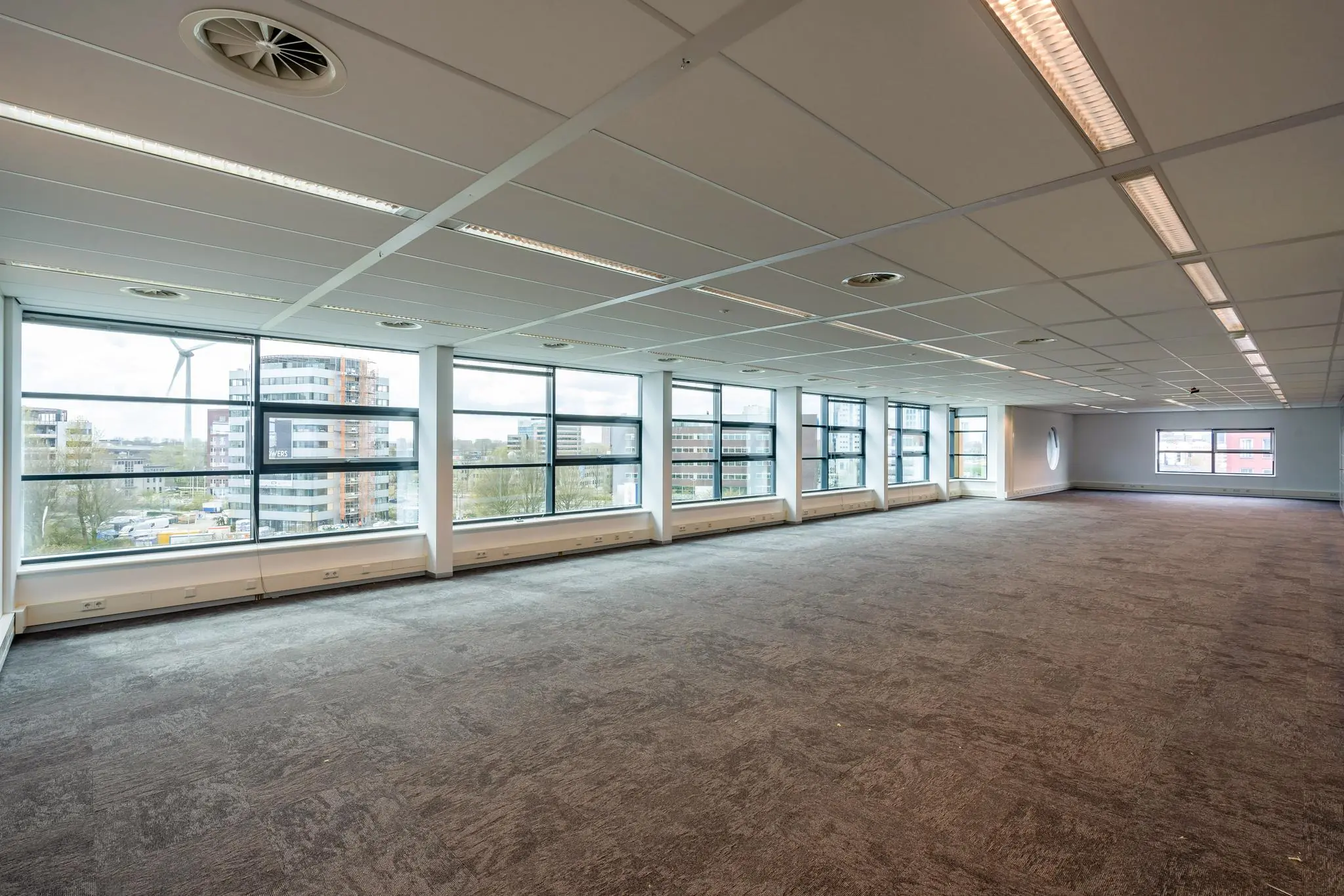 Leeg kantoorpand aan de Fascinatio Boulevard met grote raampartijen en uitzicht op moderne gebouwen.